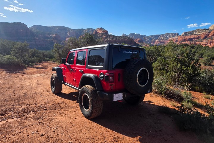 Red off-road vehicle on a dirt path with mountains in background.