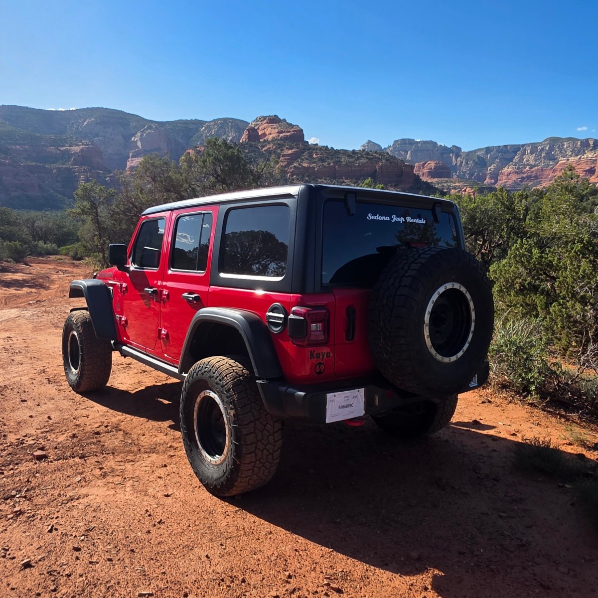 Red off-road vehicle on a dirt path with mountains in background.