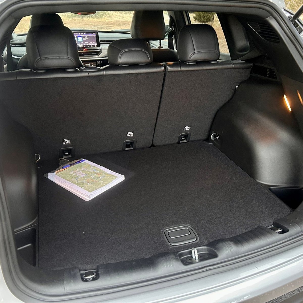 Open SUV trunk with a map book on the floor, rear seats visible.
