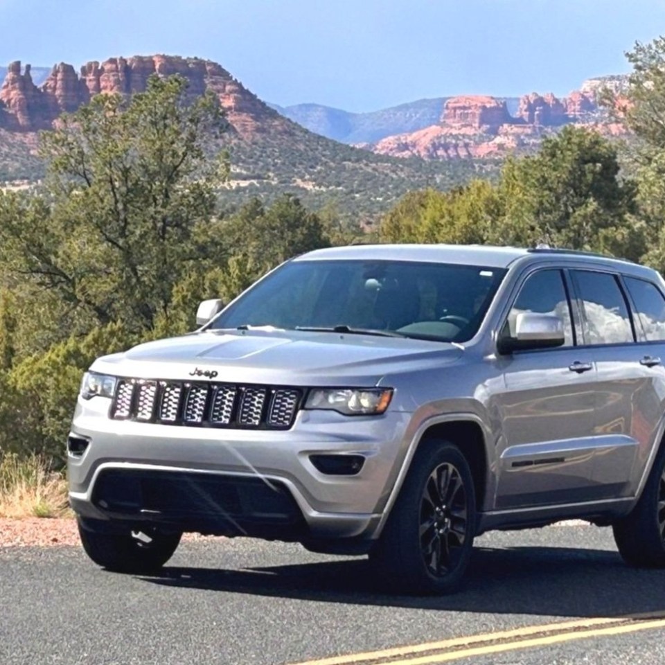 Silver SUV parked on a road with red rock formations in the background.