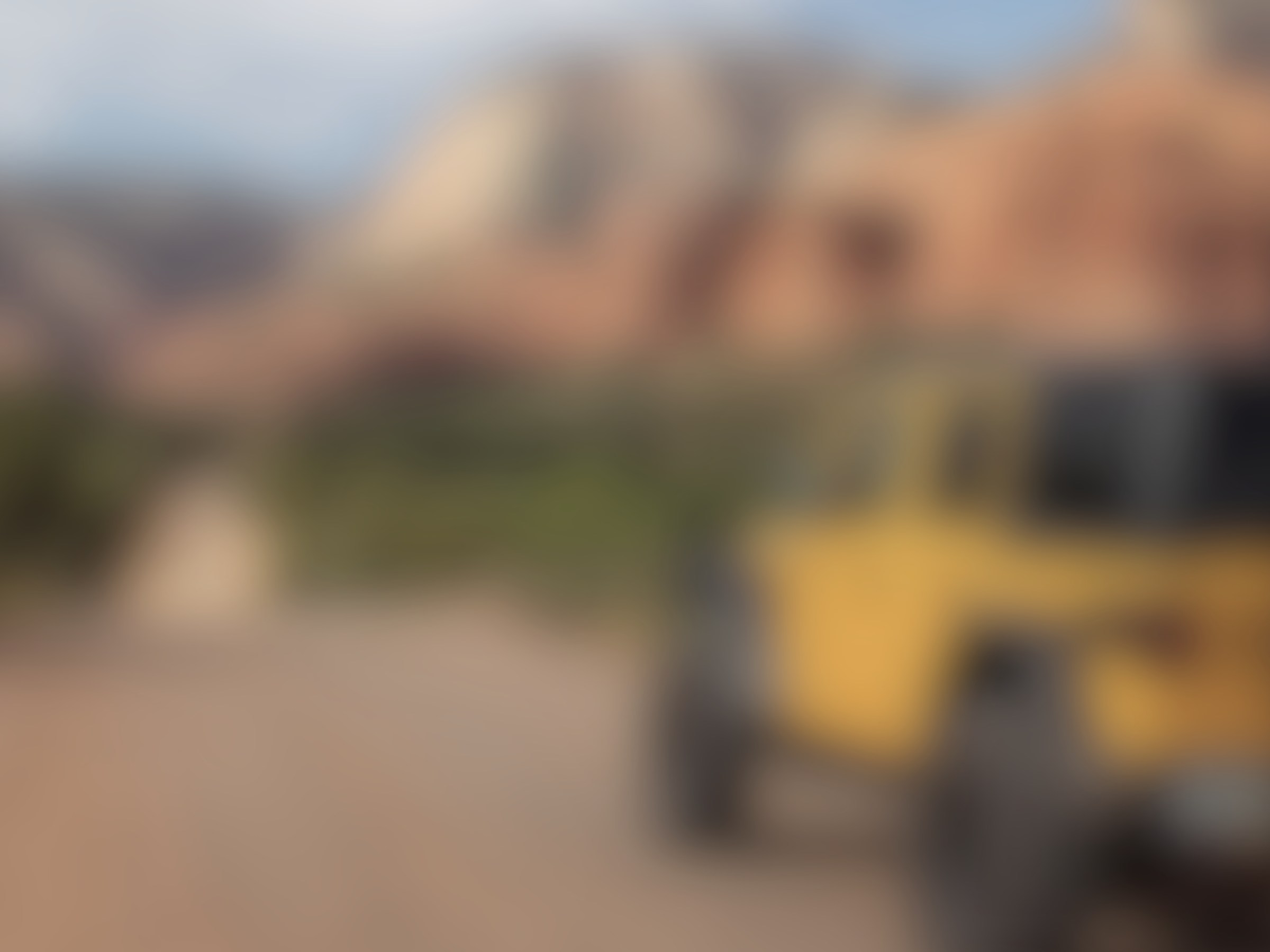 Blurred image of a yellow off-road vehicle near red rock formations.