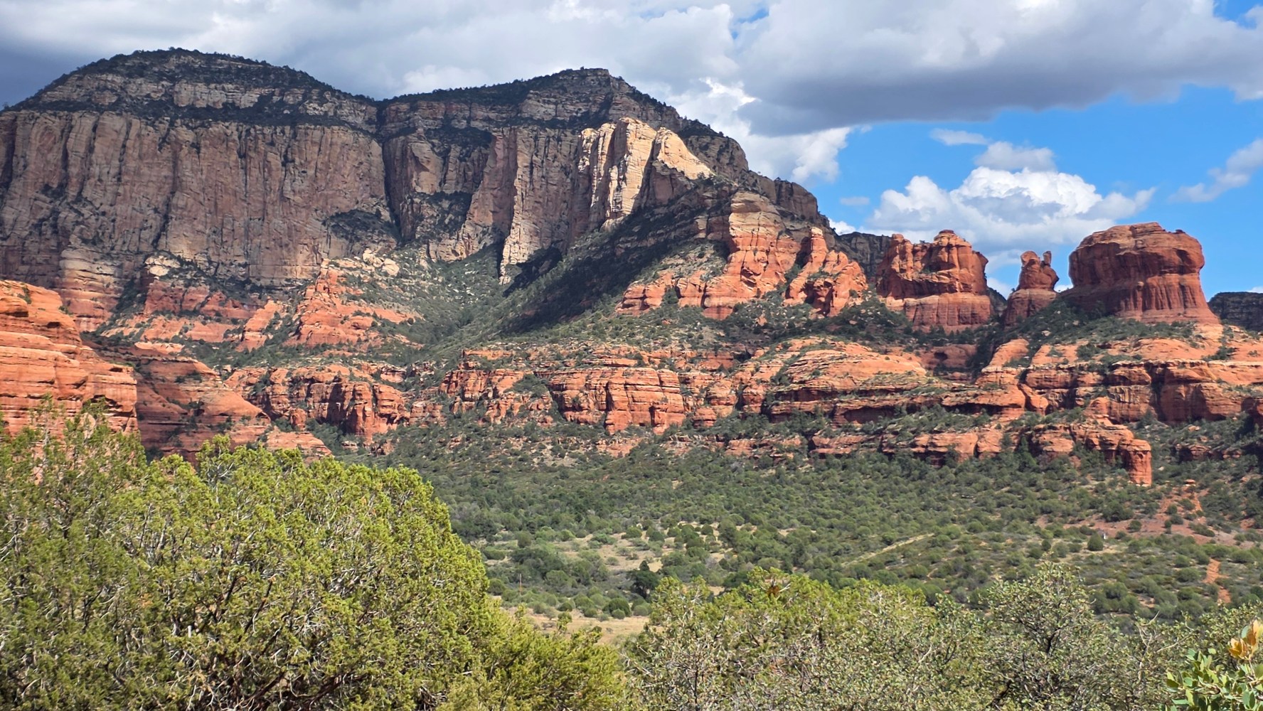 Scenic view of red rock formations under a blue sky with clouds.